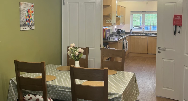 A dinning table with a view through to the kitchen beyond.