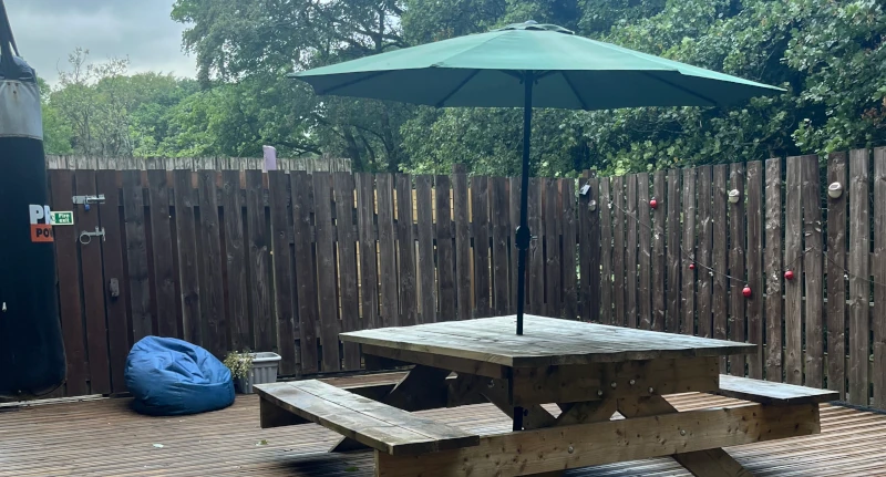The outside decking area with bench , beanbag and a parasol.